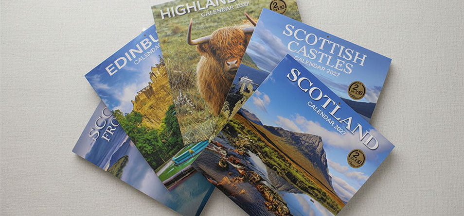 A stack of five Scotland #calendars fanned out on a light beige textured fabric background.  - Image
