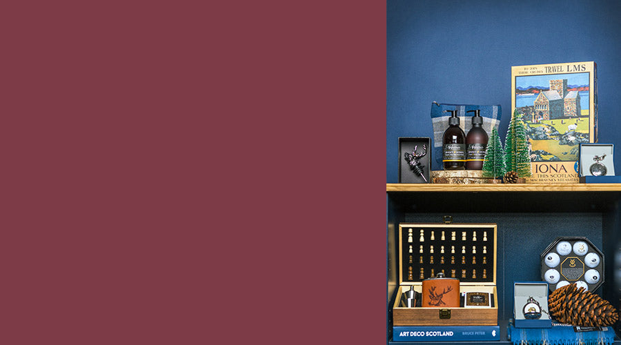 Decorative shelf with various items including a chess set, jigsaw puzzle, and St Andrews gift sets against a blue wall. - Image