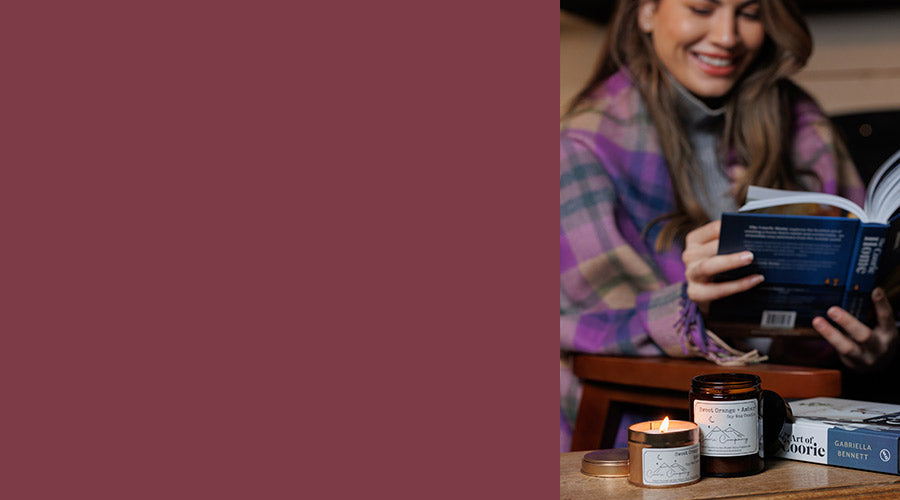 Woman reading a book with candles and a jar on a table - Image