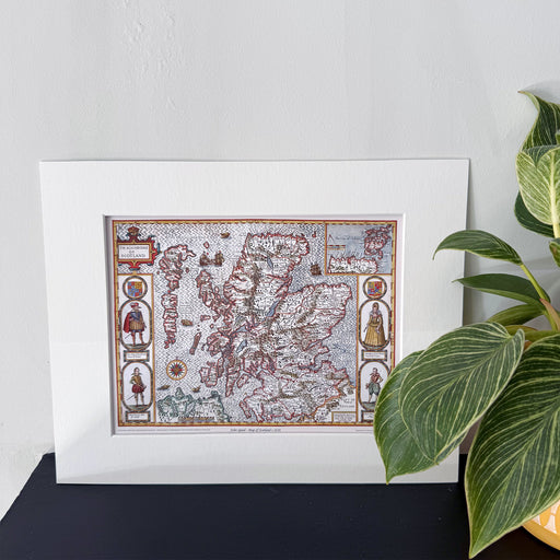 Ancient map of Scotland replica on a black mantle with green plant.  - Image