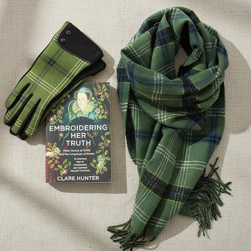 Green plaid scarf, gloves, and book titled 'Embroidering Her Truth' by Clare Hunter on a white background. - Image