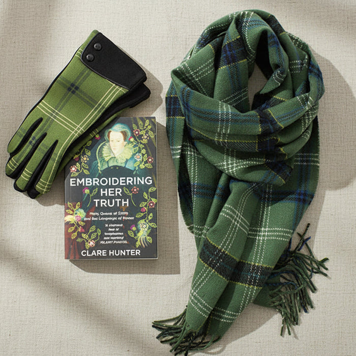 Green plaid scarf, gloves, and book titled 'Embroidering Her Truth' by Clare Hunter on a white background. - Image