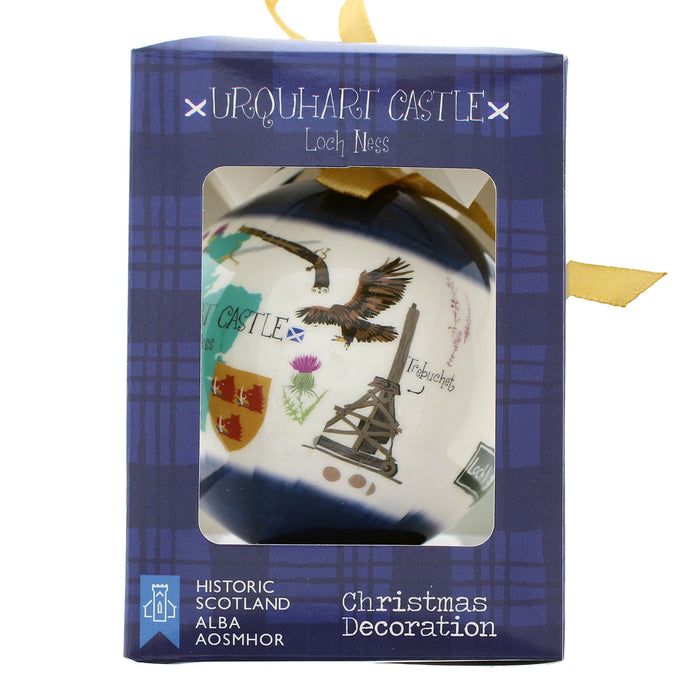 Urquhart Castle Loch Ness Christmas decoration in its original blue packaging box, featuring a printed illustration of the Scottish landscape and castle on a white ceramic-style ornament visible through a clear window. - Image