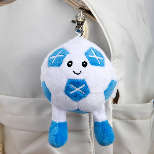 Plush keychain shaped like a cartoonish football ball attached to a beige bag. - Image