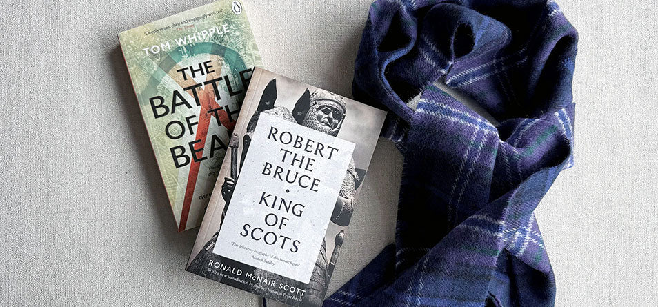Two books titled 'The Battle of The Beams' and 'Robert the Bruce, King of Scots' on a textured surface with a blue plaid fabric. - Image