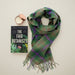 Tartan scarf, candle and a book titled The Fair Botanists are displayed against a nude backdrop - Image