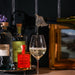 Bottle of wine being poured through the Highland Cow bottle pourer with bottles and framed pictures in the background.  - Image