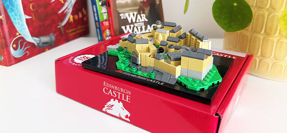 Model of Edinburgh Castle in a red box on a white surface with books in the background - Image