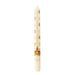 A Christmas advent candle with a cream-colored body, decorated with a printed calendar of the twelve days, small illustrations, and the Crown Jewels at the bottom. - Image