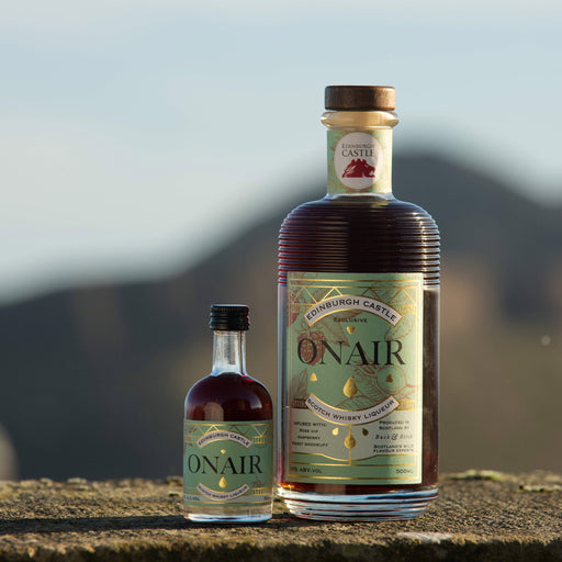 2 sizes of the whisky liqueur Onair' sit on a castle wall with Arthur's Seat in the distance.  - Image