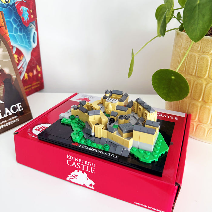 Edinburgh Castle model in a red box with a plant and book in the background - Image