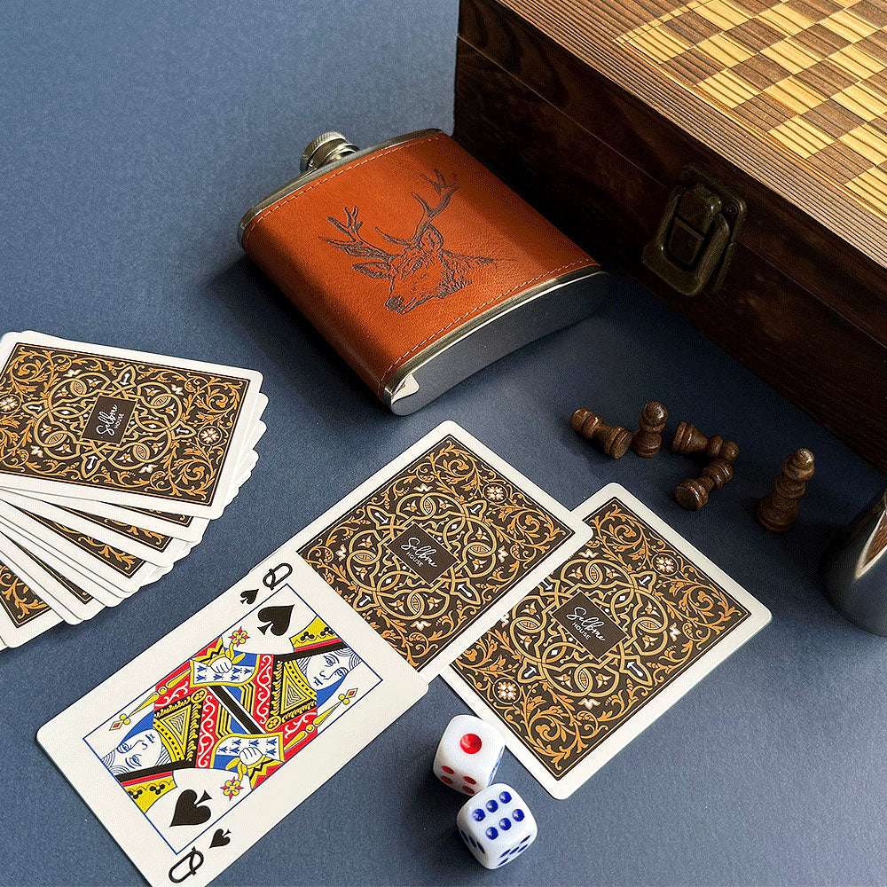 Playing cards, dice, flask, and chess pieces on a blue surface with a wooden box. - Image