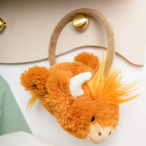 Plush highland cow ear muffs on a gold handle on a white surface - Image