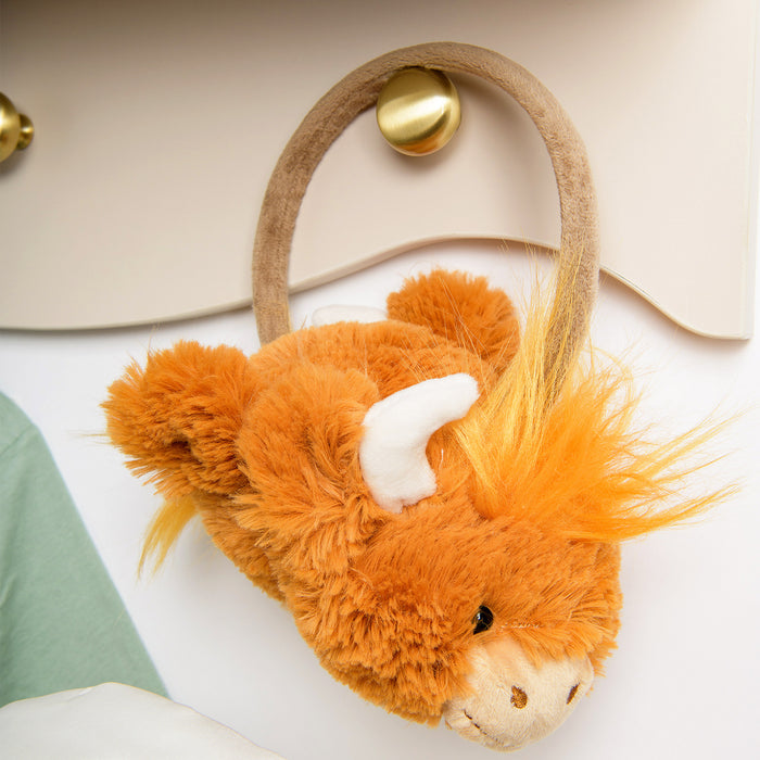 Plush highland cow ear muffs on a gold handle on a white surface - Image