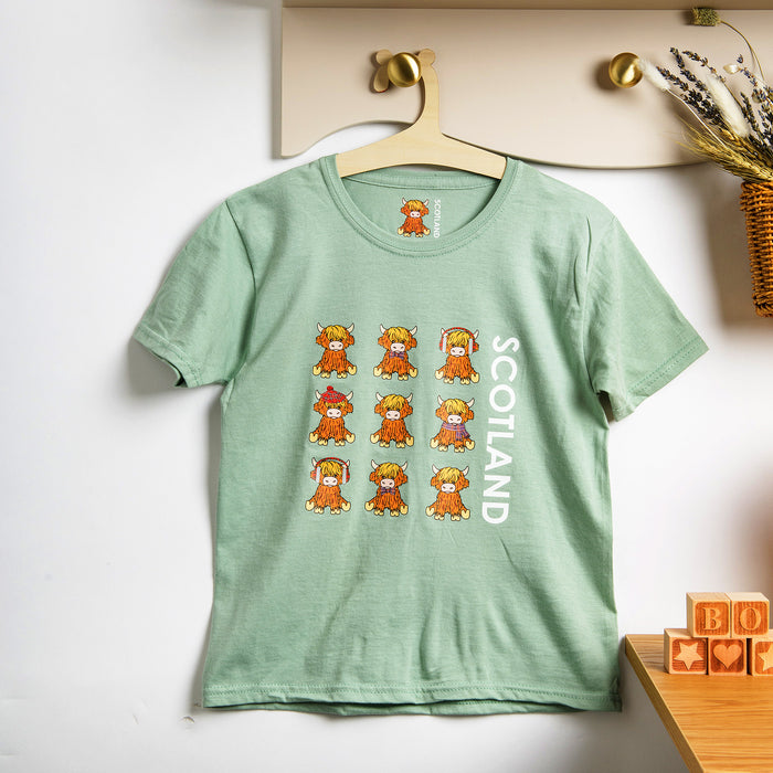Mint green kids t-shirt with highland cow print hanging on a peg against a white wall - Image
