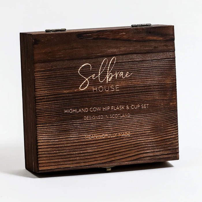 Brown wooden box with signature etched text reading 'Selbrae House', Highland Cow Hip Flask & Cup Set'.  - Image