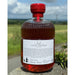 Bottle of 'Against The Grain' Hirundine whisky with a red cap against a natural landscape - Image