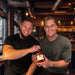 Two Scottish Rugby stars in a bar setting holding a bottle of their Hirundine Legacy Whisky - Image