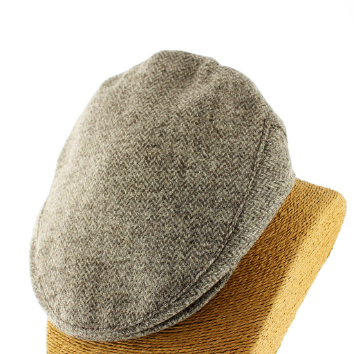 Gray flat cap on a wooden block with a white background - Image