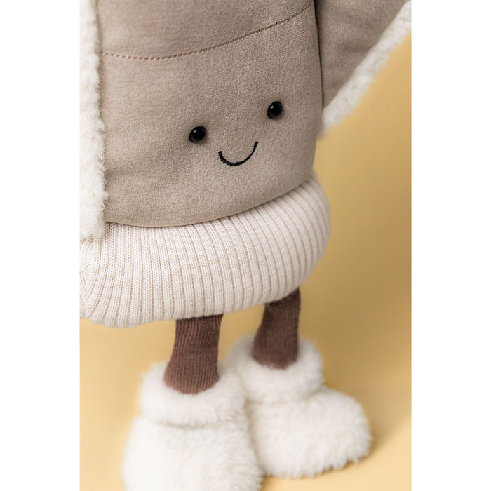 Close up of a plush soft toy in the shape of a winter mitten with wooly feet against a beige backdrop. - Image