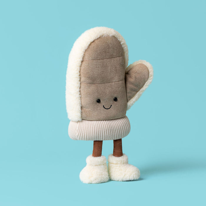 Plush knitted soft toy in the shape of a winter mitten with smiley face and furry boots. Against a blue backdrop. - Image