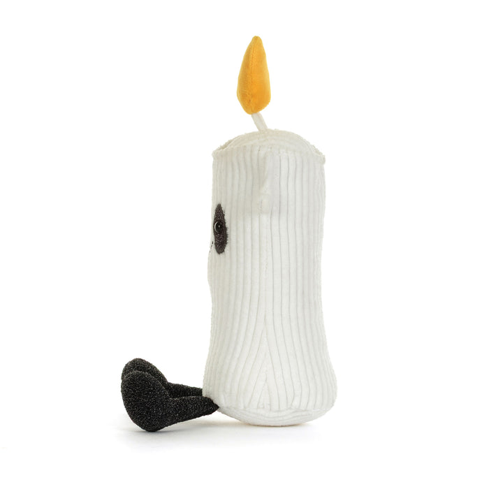 A white ribbed plush candle toy with a yellow flame on top, a small black embroidered eye, and a black textured foot, photographed on a clean white background. - Image