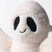 A close-up of a plush ghost toy with a soft cream-colored body, black eyes and nose, and a small black stitched smile on a plain light background. - Image