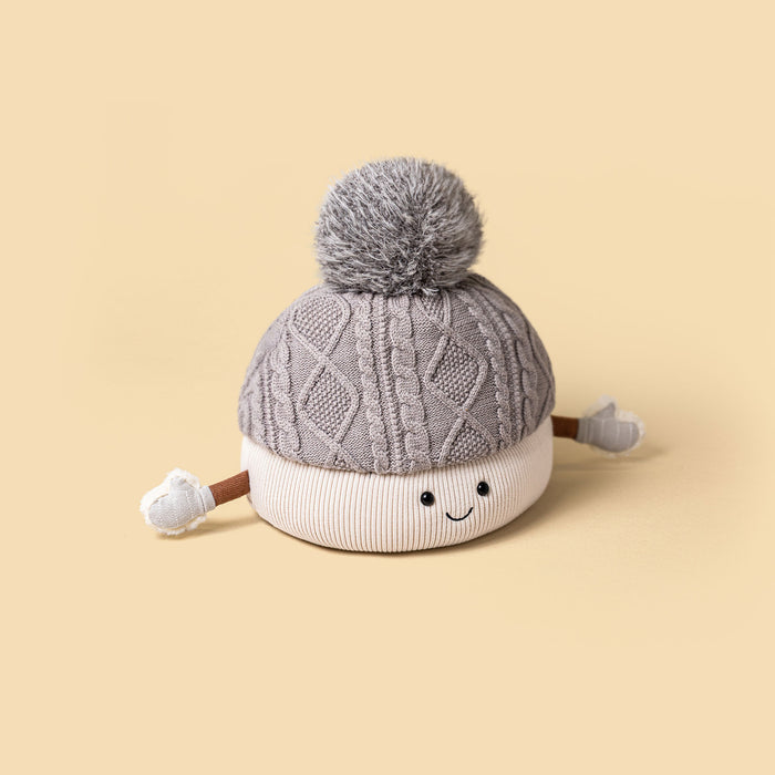 Plush knitted soft toy wearing a aran hat against a beige backdrop - Image