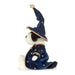 A plush dog toy dressed as a wizard, wearing a tall navy blue pointed hat and matching robe decorated with gold stars and a crescent moon, set against a plain white background. - Image