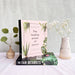 Two books on a table with decorative vases and plants. - Image