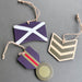 Three wooden military-style rank or flag decorations hanging from natural jute twine on a dark grey background.  - Image