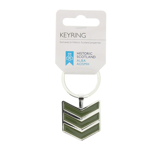 A silver-tone metal keyring with a chevron-shaped pendant featuring olive green enamel stripes, attached to a white cardboard display card.. - Image