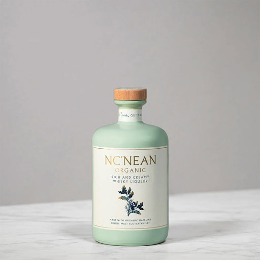 Bottle of NcNean Whisky Liqueur against a grey and marble backdrop.  - Image