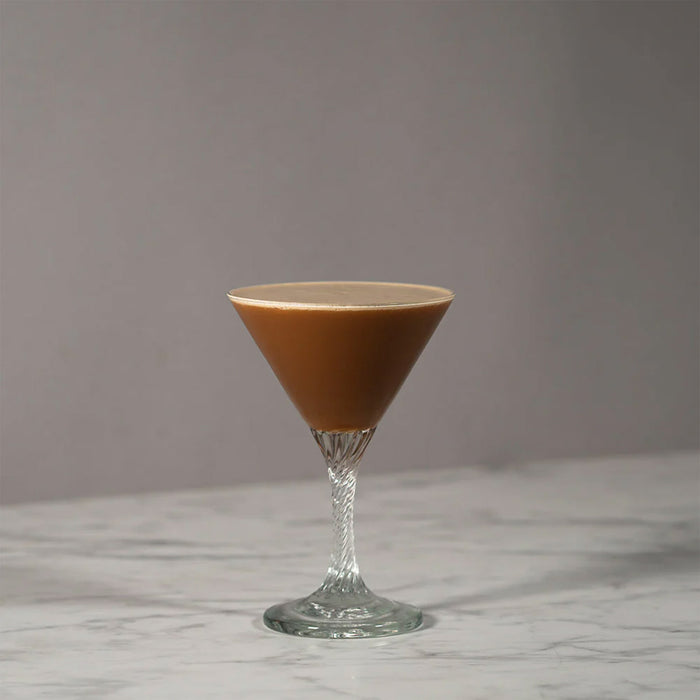 Cocktail glass containing NcNean Whisky liqueur against a grey and marble backdrop.  - Image