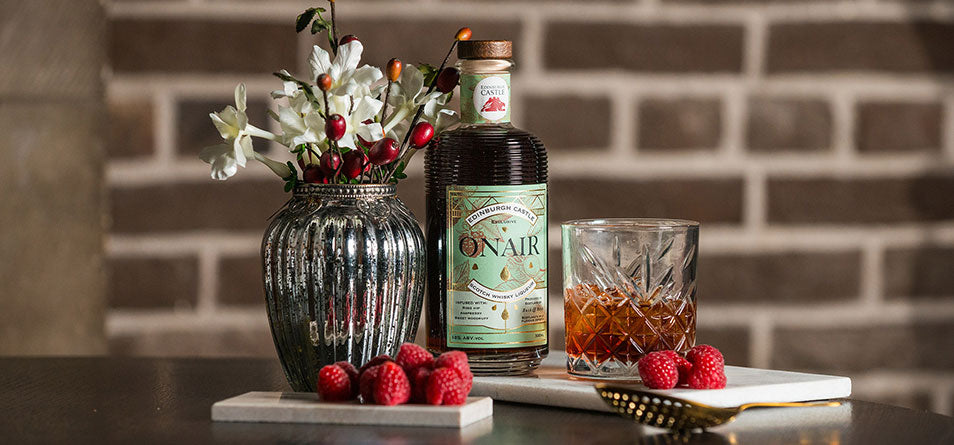 Bottle of Onair whiskey with a glass of whiskey and fruit on a marble surface against a brick wall. - Image