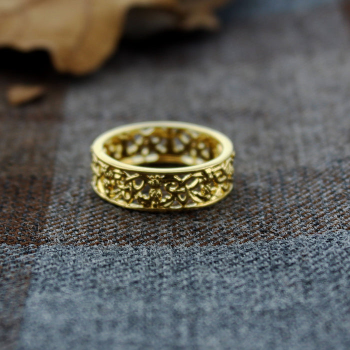 Gold ring with intricate design on a textured surface - Image