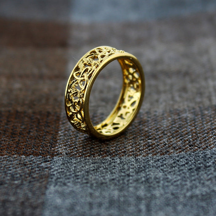 Gold ring with intricate design on a textured surface - Image