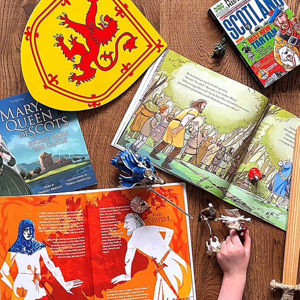 selection of scottish childrens book pages lie open as young boy plays with knight models on floor