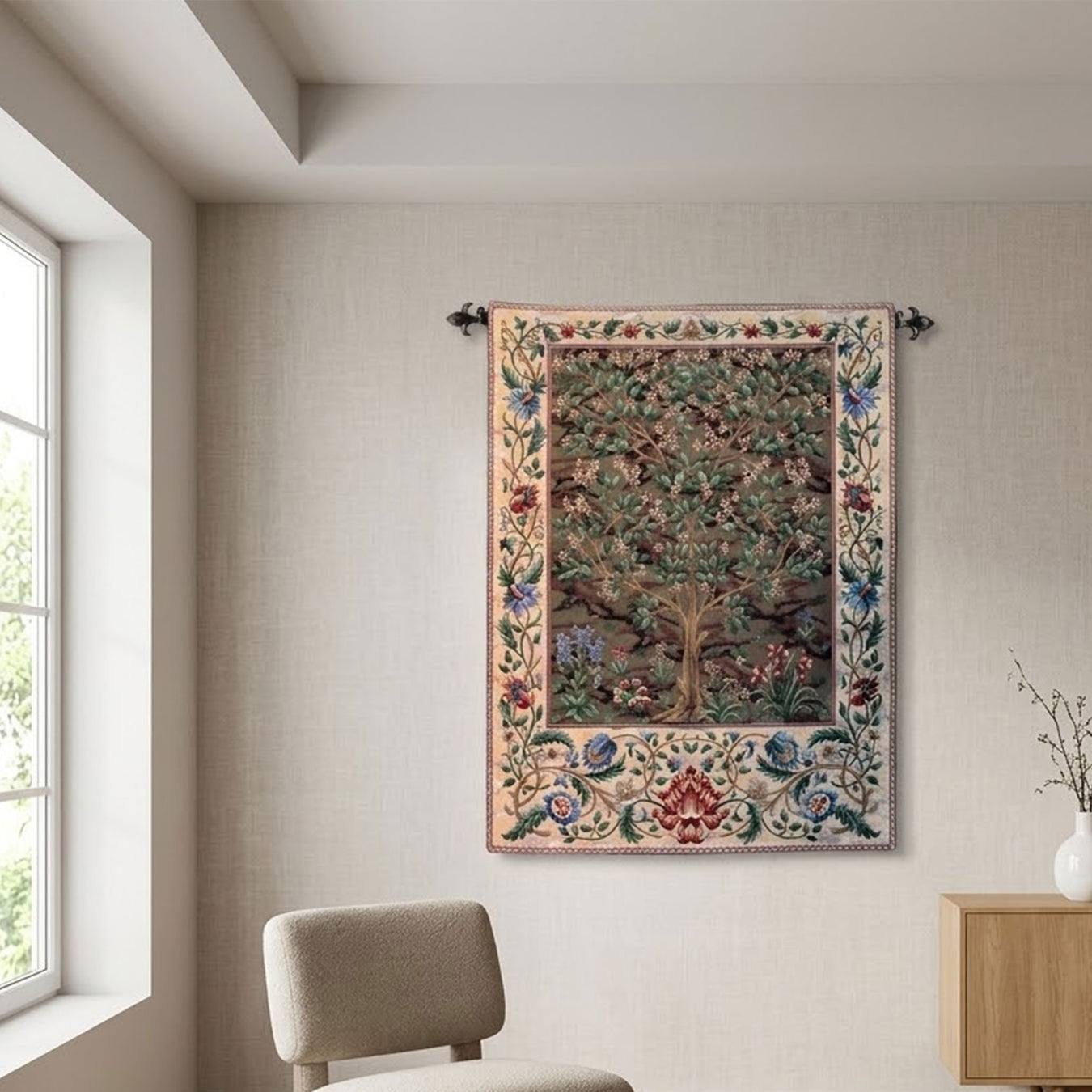 A large, detailed tapestry featuring a 'Tree of Life' design with a floral border, hanging on a textured beige wall in a modern room setting with a chair and side table visible. - Image