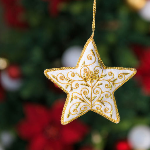 Decorative star ornament with gold embroidery on a blurred Christmas tree background - Image