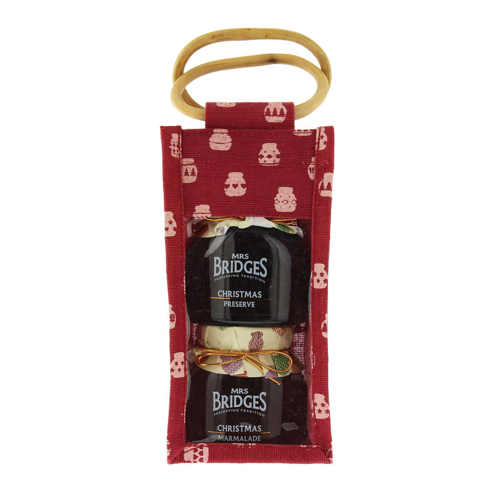 A Christmas-themed gift set from Mrs. Bridges, featuring two jars of preserves in a red fabric pouch with a gold-colored hanging loop, shown against a plain white background. - Image