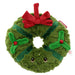 A plush green Christmas wreath toy with a red bow, green ribbon accents, holly details, and embroidered eyes, shown on a plain white background. - Image