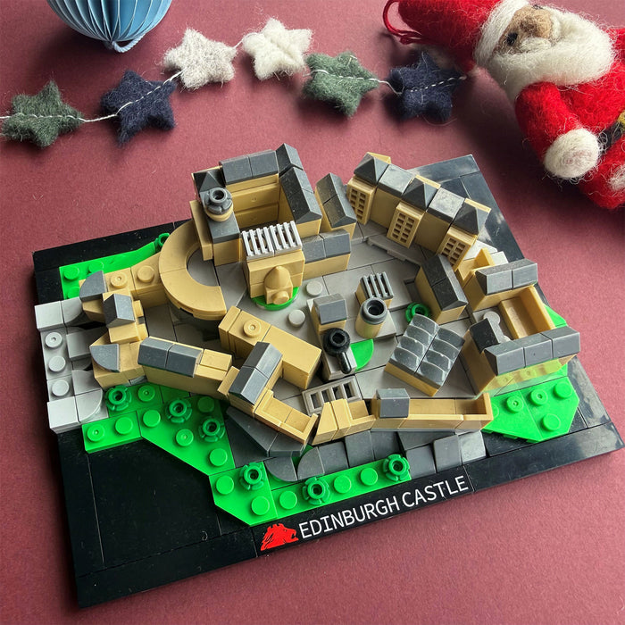 interlocking brick build depicting Edinburgh Castle surrounded by felt decorations against a maroon backdrop - Image