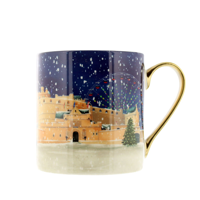 A ceramic mug featuring a winter night scene of a castle under a snowfall, with a gold-colored handle on a white background. - Image