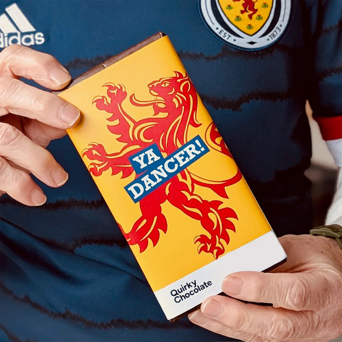 Person holding a 'YA DANCER!' chocolate bar with a lion design on a blue background - Image