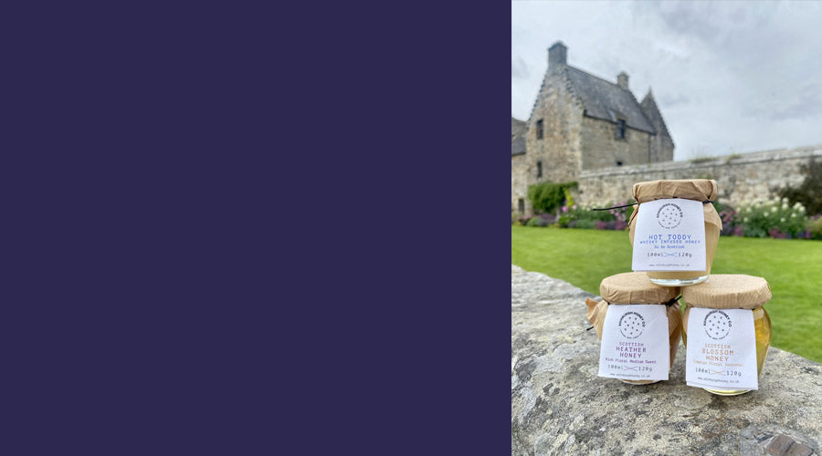 3 jars of honey stacked sitting in front of aberdour castle on stone wall in the gardens