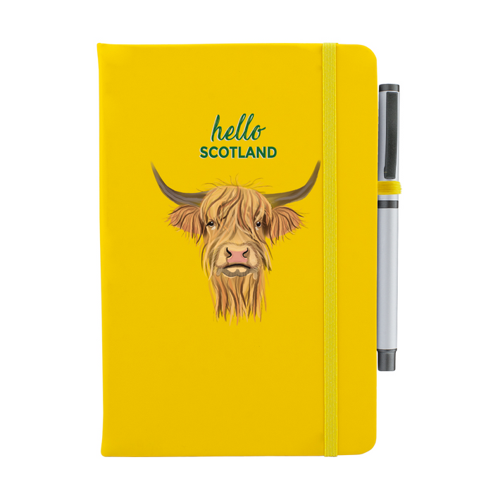 Yellow soft feel note pad with a highland cow motif. the text above reads 'hello SCOTLAND' and comes with a silver pen attached.