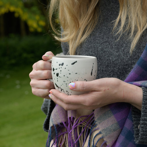 speckled large coffee mug being held in models hands