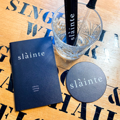 slainte leather whisky tasting notebook shown on table top with other items from the collection