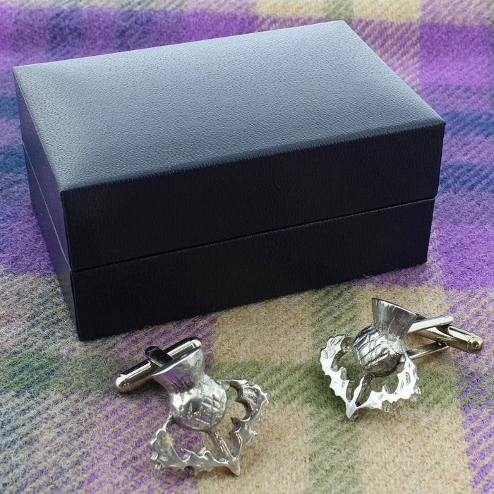 thistle cufflinks shown with presentation box on a tartan blanket background